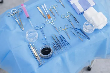 Delicate stainless steel plastic surgery instruments and micro-surgical tools neatly arranged on a blue sterile tray.